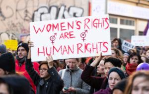 Demonstration in Berlin, Germany, March 8 2019. The demonstrators are holding a sign that reads Women's Rights are Human Rights in red. Graffiti in the background.